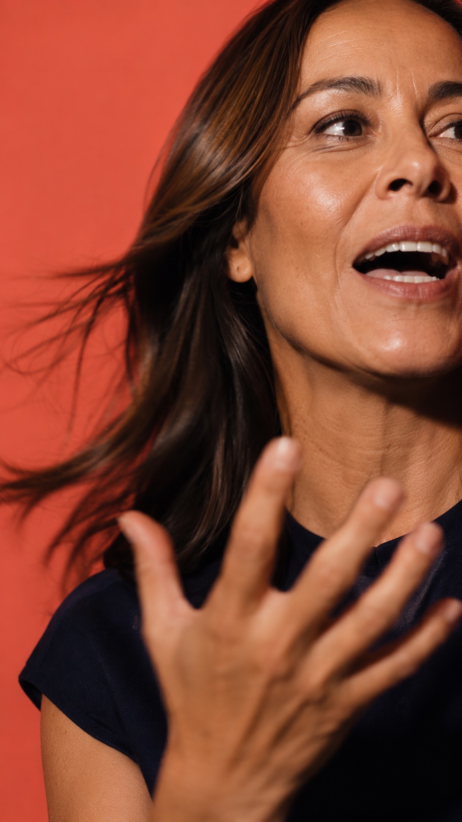 Mujer expresándose con energía frente a un fondo coral